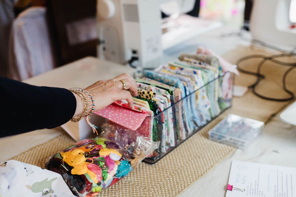 Sewing table with assorted fabrics, thread, and crafting tools