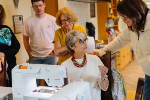Instructor teaching adults how to sew using a sewing machine