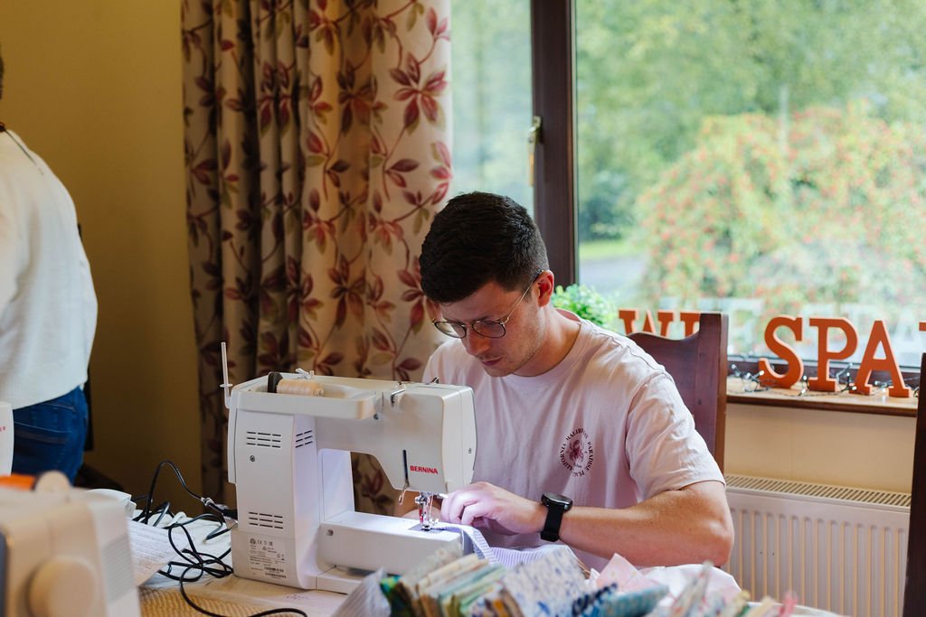 Man learning to sew during a WeSpark creative workshop.